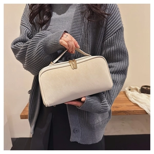 Détail du sac de toilette crème avec poignée large et doubles zips dorés