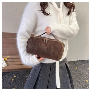 Détail d'une trousse de toilette marron effet daim avec fermetures éclair dorées