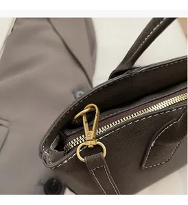 Macro shot of gold-tone hardware and stitching on a dark brown suede dumpling bag