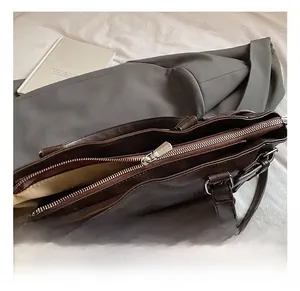 Close-up of top metal zipper and smooth silver hardware on dark brown tote bag