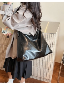 Close-up of black glossy hobo bag with vintage crinkle texture worn by a model