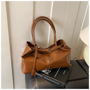 Close-up of brown glossy faux leather shoulder bag on books showing luxury texture