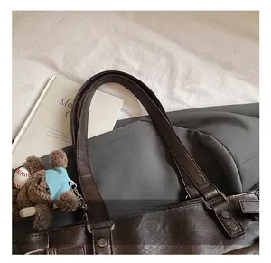 Detail of soft brown leather tote handle with fine stitching and cute bear charm accent
