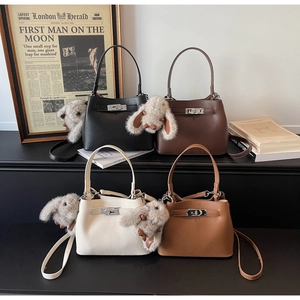 Detail of four litchi leather trapezoid bucket bags in various colors with metal twist locks