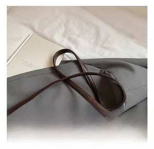 Detail of adjustable dark brown leather shoulder strap with silver buckle on tote bag