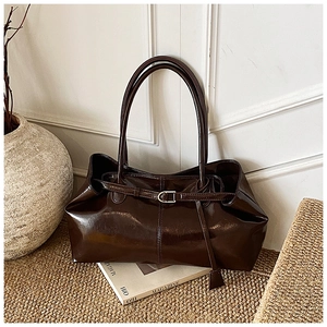 Detail of dark brown glossy patent leather tote with silver buckle and dual handles