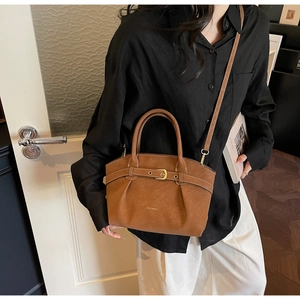 Close-up of caramel leather handbag with decorative strap and adjustable shoulder strap