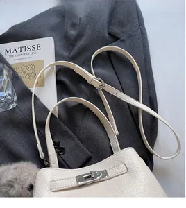 Detail of cream pebbled leather handbag with silver turn-lock and adjustable shoulder strap