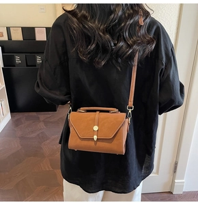 Close-up of vintage brown crossbody bag with matte texture and golden shield buckle