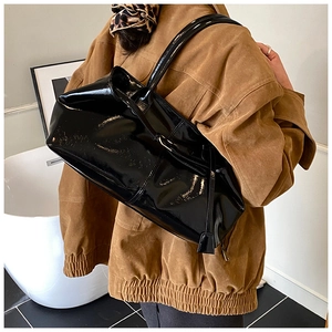 Detail of high-gloss black patent leather tote bag with elegant side ribbon decor