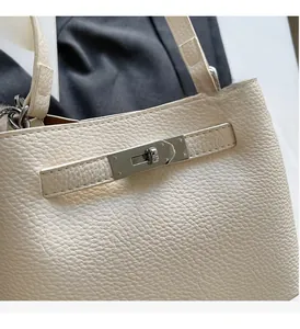 Close-up of cream lychee-grain leather texture and polished silver metal twist lock buckle