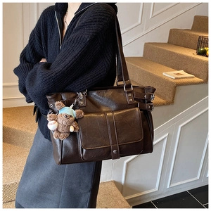 Detail of vintage brown tote bag with plush bear charm and magnetic flap pocket
