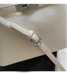 Detail of cream lychee leather bucket bag featuring silver twist lock and adjustable strap