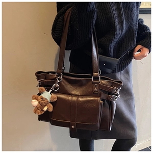 Detail view of deep brown vintage tote bag with metal buckles and cute plush bear charm