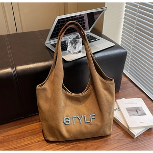Detail of a large brown canvas tote bag with GTYLF blue embroidery in a modern office setup