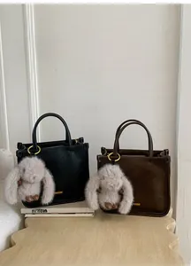 Detail of retro oil wax leather bags in black and brown with plush charms and gold hardware