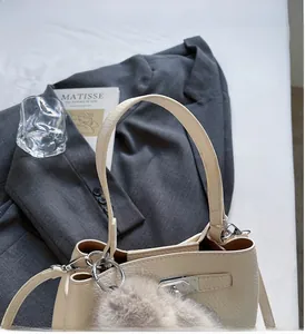 Detail of cream-white lychee grain leather bucket bag with silver hardware and fur pom-pom