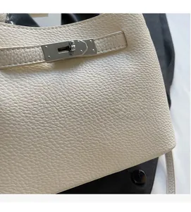 Macro shot of off-white lychee grain leather bucket bag with silver metal twist lock closure