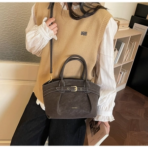 Detailed view of dark brown textured bag with decorative buckle and detachable strap