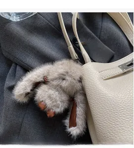 Detailed view of plush rabbit bag charm on leather bucket bag with metallic clip accessory