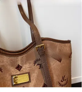 Close-up of brown jacquard tote bag with leather trim and gold metal logo plaque