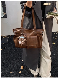 Detail of vintage brown leather tote bag with front flap pocket and cute bear charm