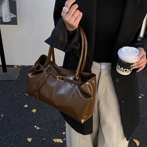 Detail of dark brown glossy patent leather tote bag with vintage minimalist design