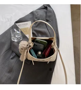 Detail showing the spacious interior of the cream bucket bag with daily essentials inside