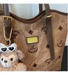 Close-up of brown monogram tote bag with canvas texture and gold metal hardware detail