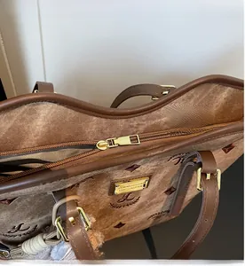 Detail of smooth metal zipper and brown leather handle on embroidered suede tote bag