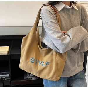Detail of camel canvas tote with blue GTYLF embroidery and brown leather handles