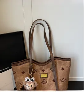 Detail of vintage brown tote bag featuring embroidery and adjustable leather handle