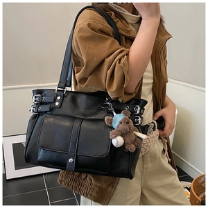 Detail of vintage black tote bag with silver buckles, studs and a cute bear charm