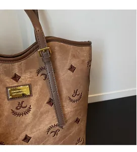 Detailed macro view of the jacquard fabric texture and golden metal logo on the brown tote bag