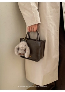 Détail d'un cabas en cuir marron foncé avec un porte-clés lapin en peluche doux