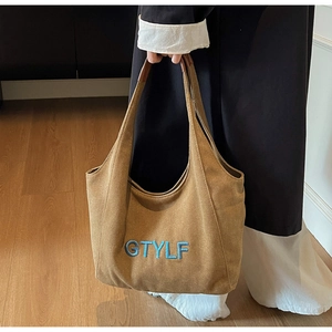 Detail of dark brown canvas tote bag with blue letter embroidery and sturdy shoulder strap