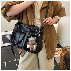 Detail view of black functional tote bag featuring metal buckles and a cute bear charm