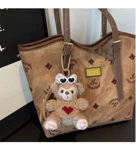 Detailed view of brown tote bag with embroidery texture and cute plush bear charm