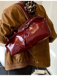 Vintage burgundy large tote bag in glossy leather worn over the shoulder by a model