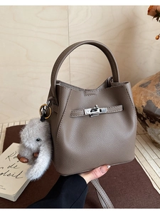 Dettaglio borsa a secchiello in pelle taupe con chiusura argento e ciondolo a coniglio