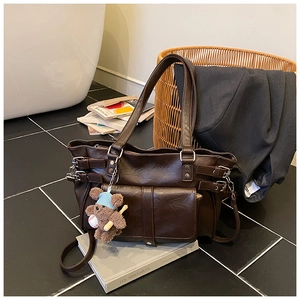 Detail of dark brown vintage tote bag featuring utility pockets and a cute bear charm