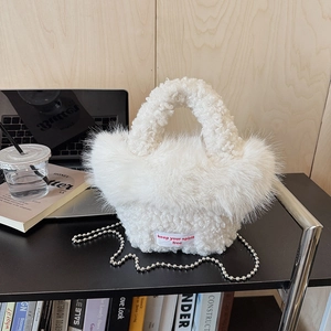Detail of white faux shearling mini bag with metallic bead chain and red label text