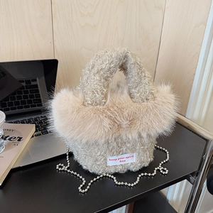 Detail of plush beige faux fur handbag with embroidered slogan and silver bead chain