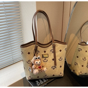 Detail of canvas tote bag featuring star embroidery and a plush bear pendant charm