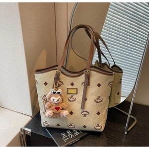 Detail of beige canvas tote with brown leather handles and ShellieMay plush charm