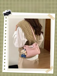 Sac seau rose avec fermoir argenté et charm ours en peluche porté en bandoulière