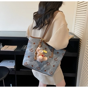 Detail of light blue tote bag with brown embroidery and plush alpaca pendant on shoulder