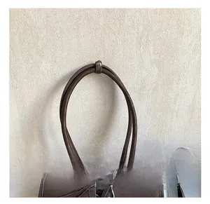 Détail de la poignée en cuir marron texturé avec sangle vintage et boucle métallique