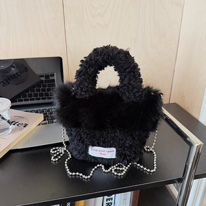 Detail of black faux fur handbag with white spirit label and silver metal bead chain strap