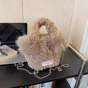 Detailed macro of a plush faux fur handbag featuring a silver chain and woven spirit label